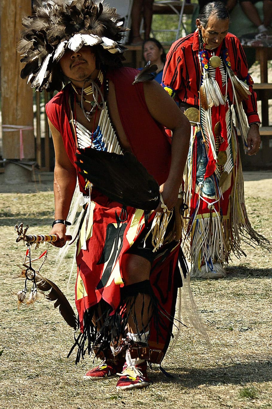 male native american holding spear standing on grass field HD wallpaper