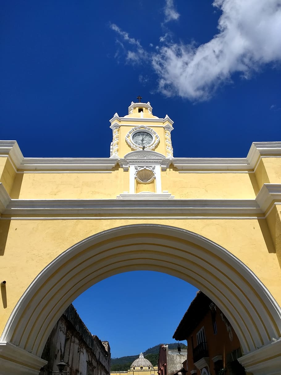 yellow and white concrete arch under blue and gray skies, architecture