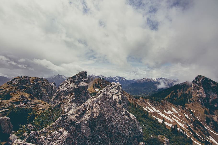 brown rock mountain covered with trees under white cloudy sky, mountains under white clouds HD wallpaper