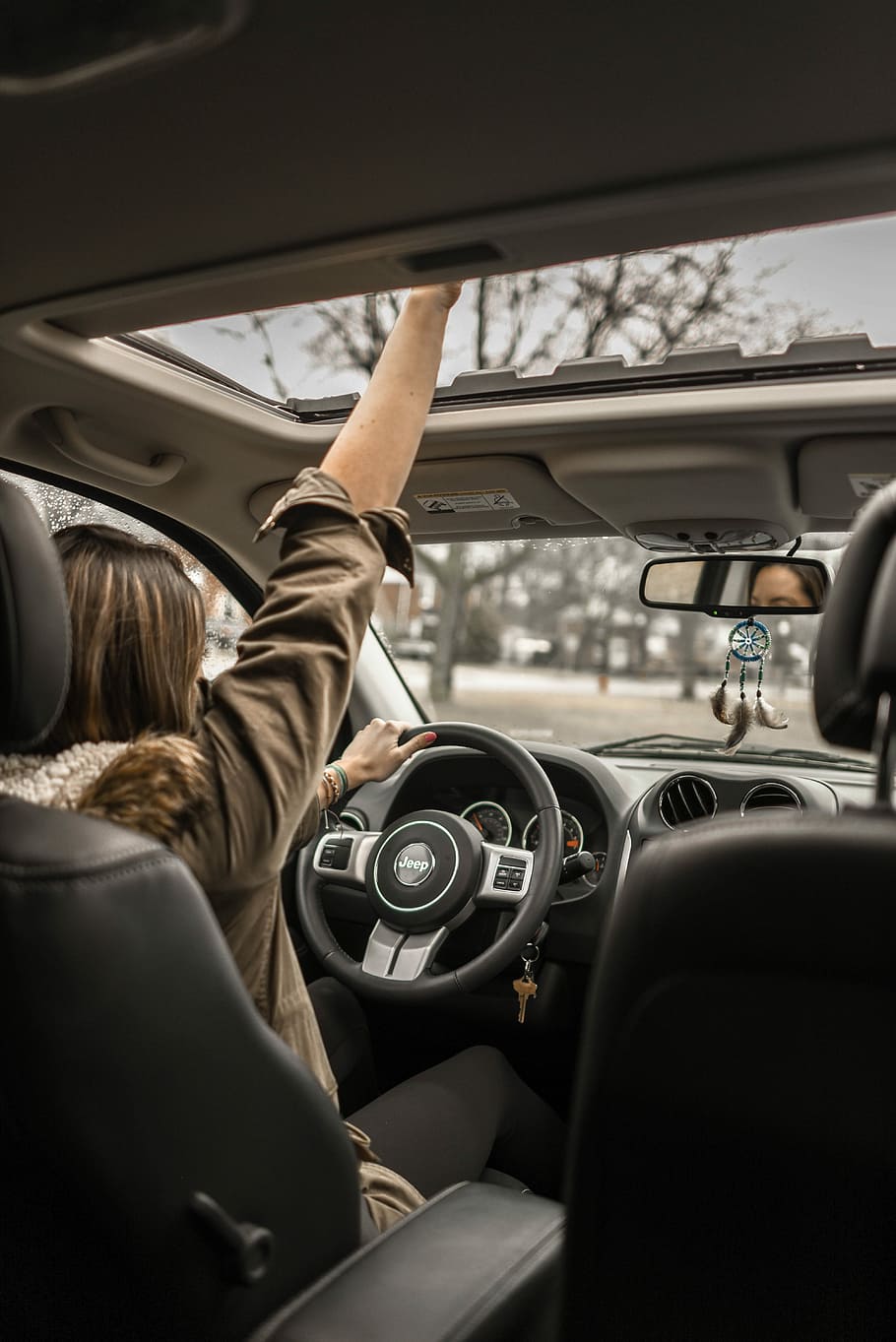 woman raising her right hand inside black and brown vehicle, woman driving Jeep vehicle, HD wallpaper