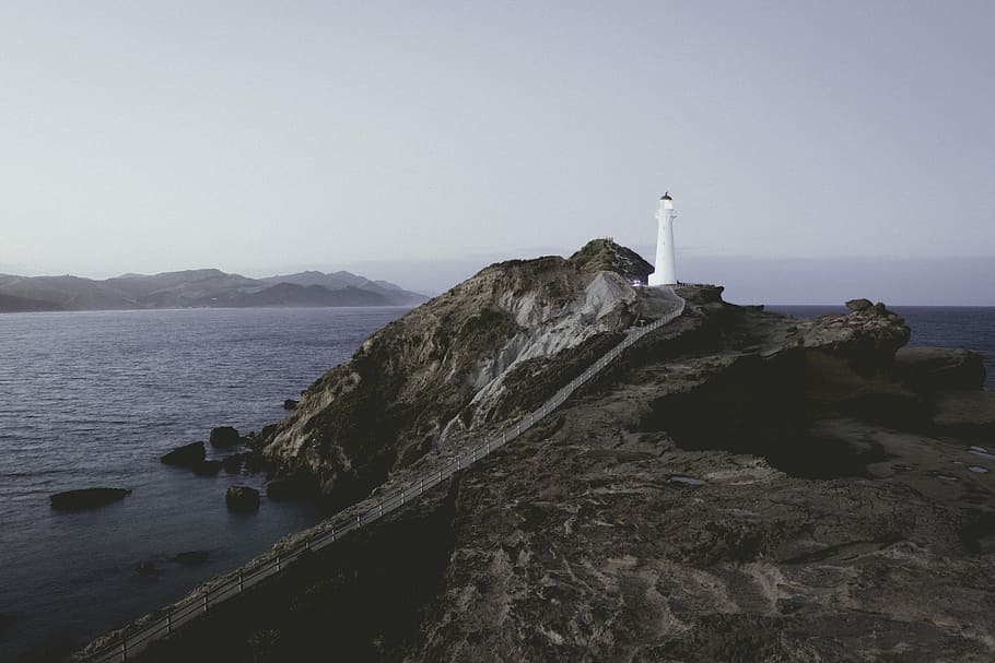 A evening at the sea, white lighthouse on mountain near shore HD wallpaper