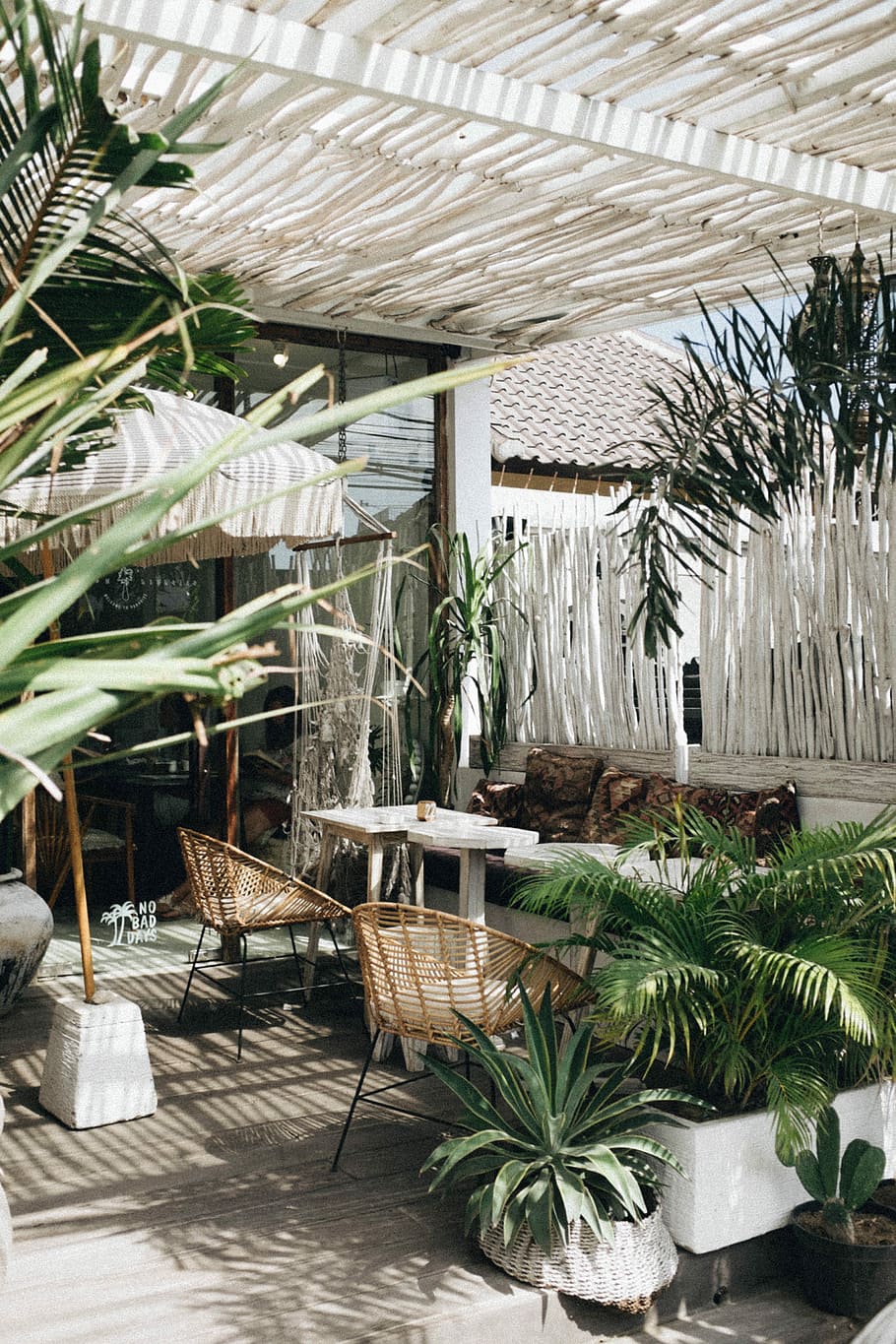 white table with brown wicker chair beside plants, empty chairs near white tables HD wallpaper