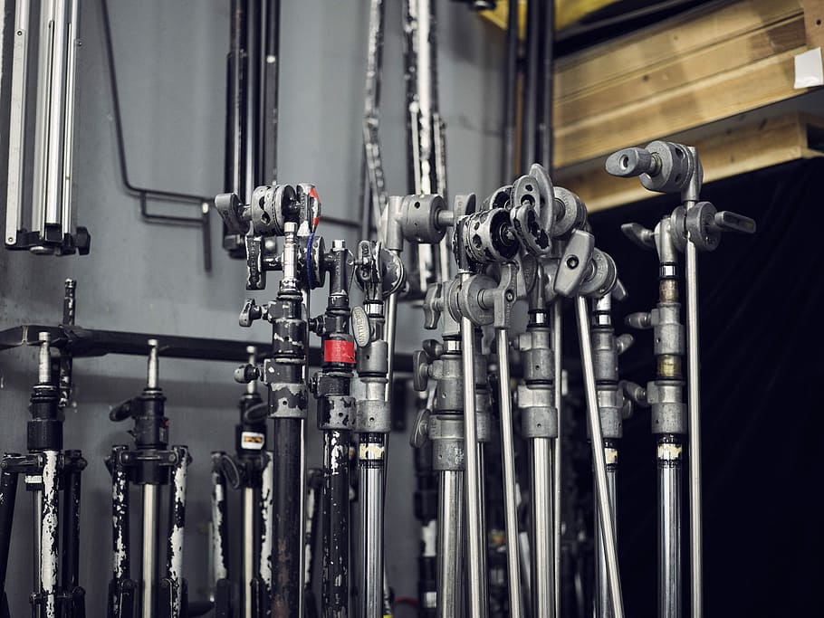 camera tripod stand lot beside wall, focus photograph of black tripods HD wallpaper