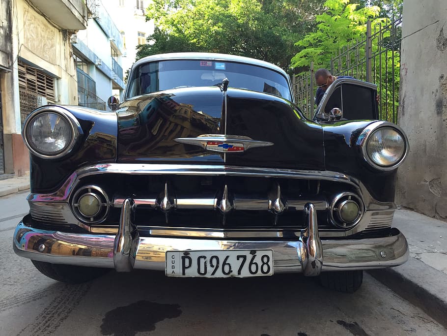 man standing beside 1951 black Chevrolet Bel Air near concrete wall HD wallpaper