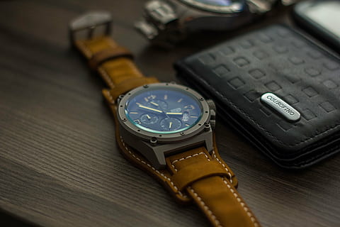 round chronograph watch beside black leather bi-fold wallet on wooden surface HD wallpaper