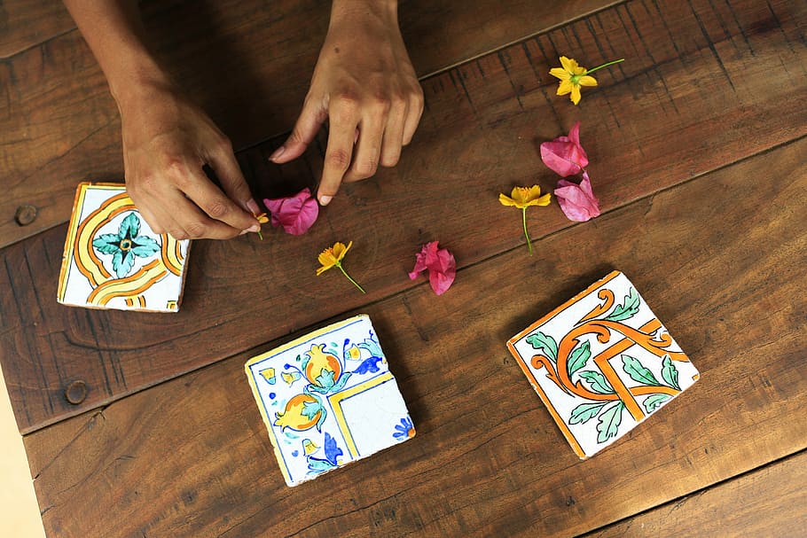 person holding pink flower petal on brown parquet floor, person touching yellow and pink flowers on top of table HD wallpaper