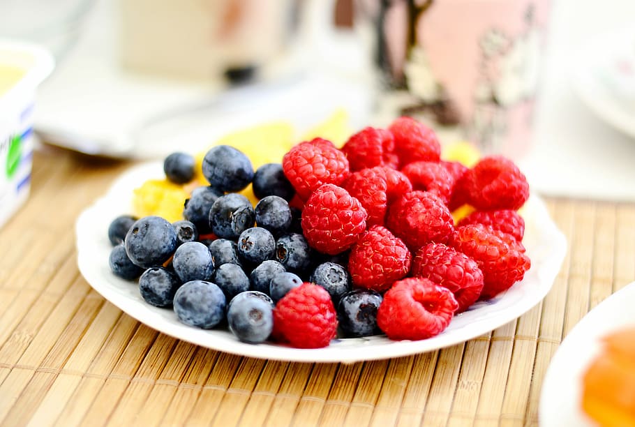 strawberries and blue berries on palte, shallow focus photography of bluberries and cranberries HD wallpaper