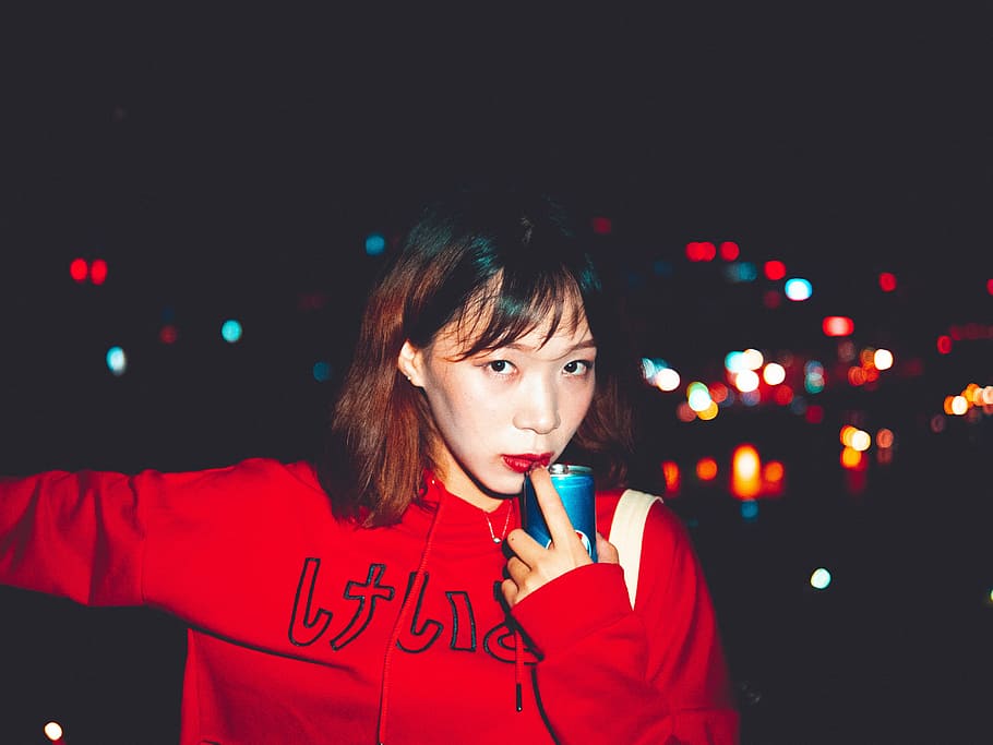 woman holding blue bottle while her index finger touching her red lips HD wallpaper
