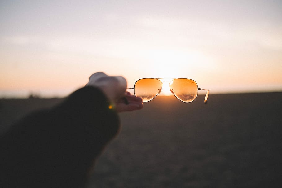 person holding brown sunglasses, person holding orange aviator sunglasses HD wallpaper