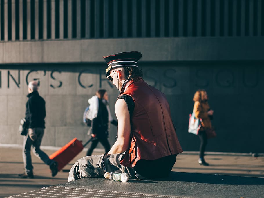 man sitting on board, pavement, beside, concrete, building HD wallpaper