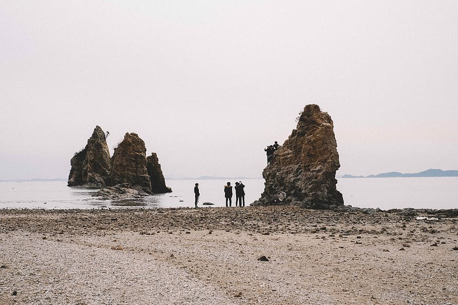 three people standing near brown rock formation, group of people gathering near brown rock HD wallpaper