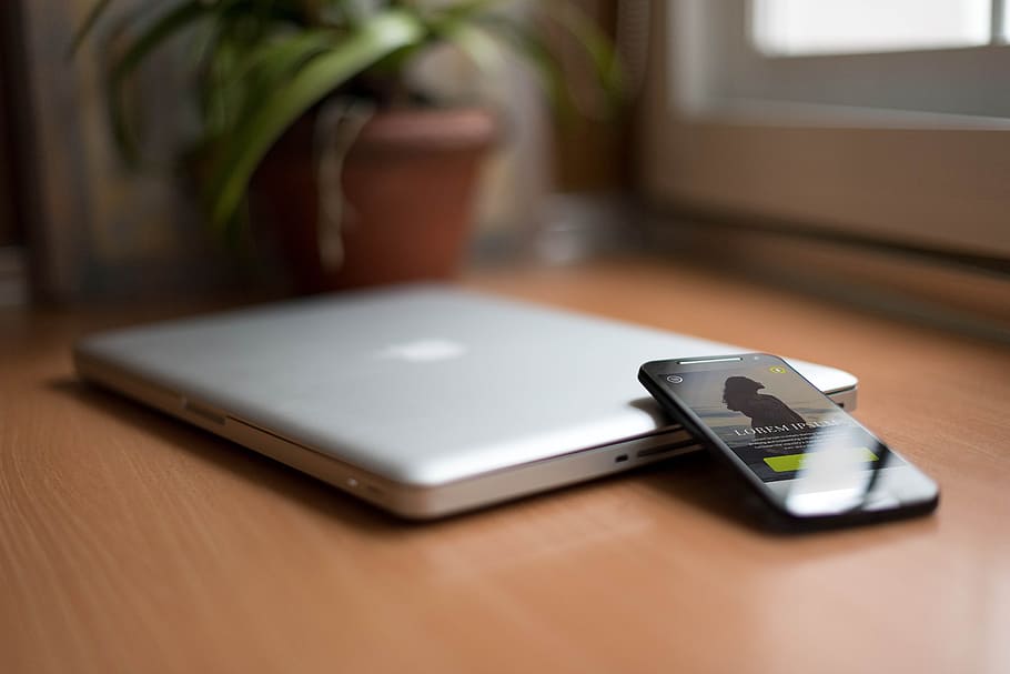 Smartphone Beside Silver Macbook on Brown Wooden Table With Potted Plant in the Background HD wallpaper