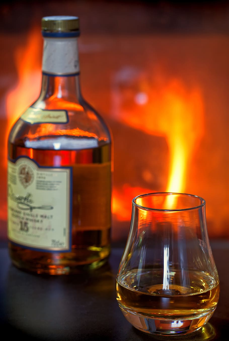 bottle beside brandy glass filled with liquor, whisky, whiskey
