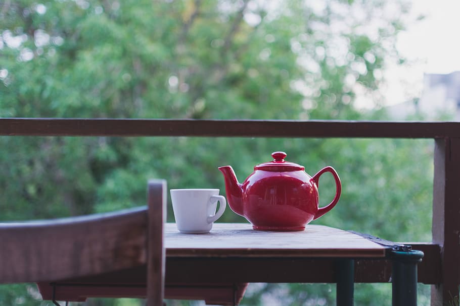 selective focus photo of red ceramic teapot and white ceramic teacup on brown wooden table near tree during daytime, selective focus photography of red teapot and white ceramic teacup on table near on balcony HD wallpaper