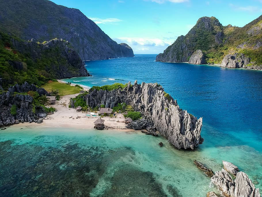 aerial photo of body of water between mountains, nipa hut beside rock formations near lake during daytime HD wallpaper