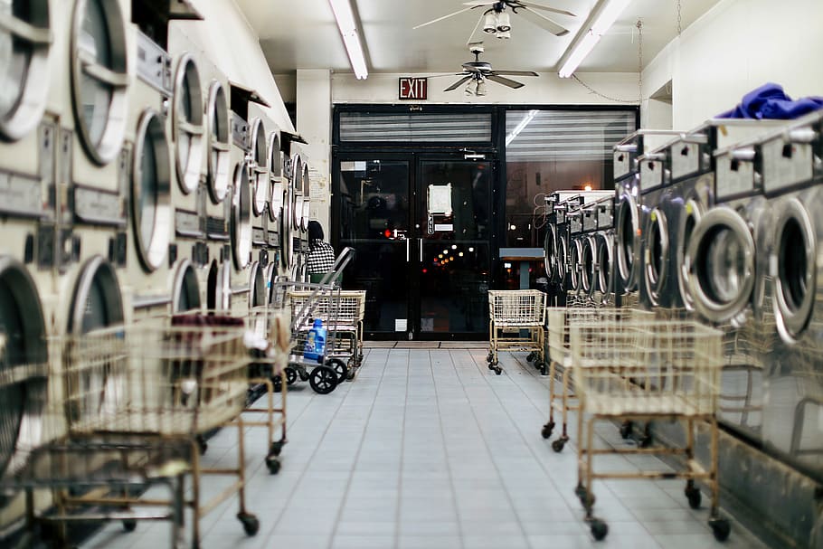 photo of empty laundy shop, silver front-load washing machines in front carts