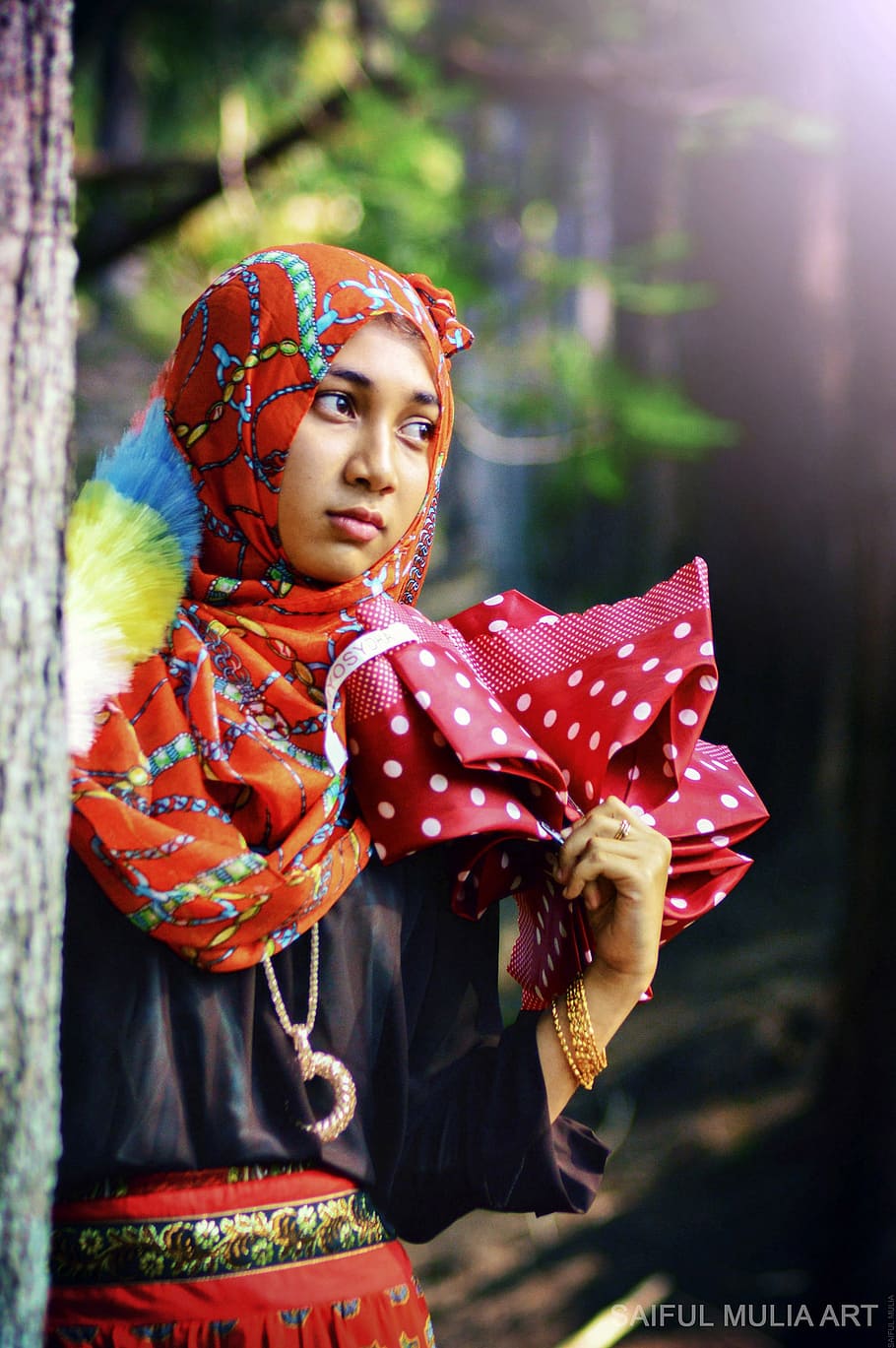 fashion photography of woman wearing multicolored hijab and black batwing top beside tree