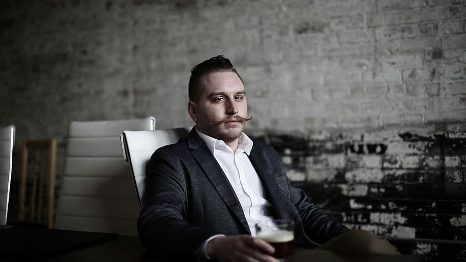 man sitting on white chair inside room, man sitting on chair holding glass of black liquid HD wallpaper