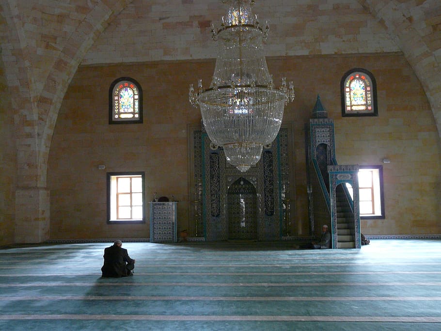 person sitting under chandelier, mosque, prayer room, prayer hall