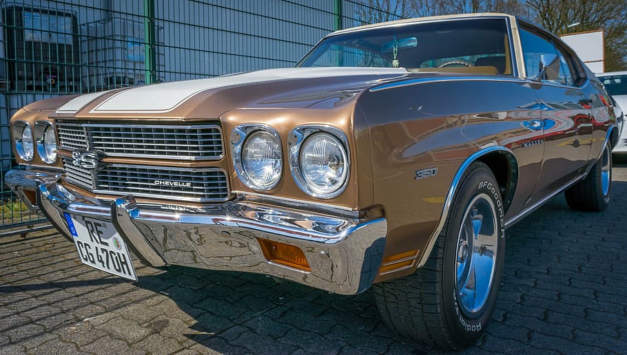 brown Chevrolet Chevelle SS coupe on road beside gray metal fence at daytime HD wallpaper