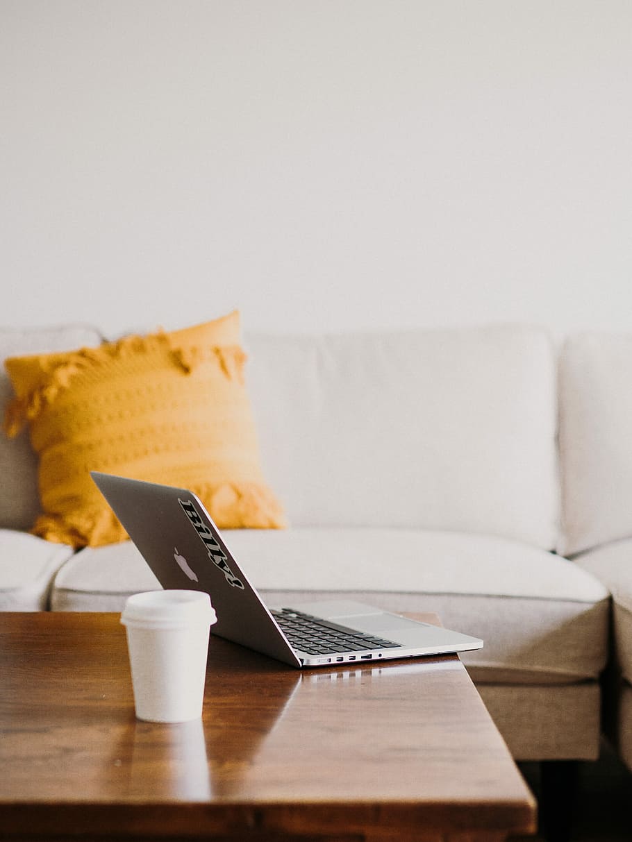 MacBook on coffee table, silver MacBook open near plastic cup HD wallpaper