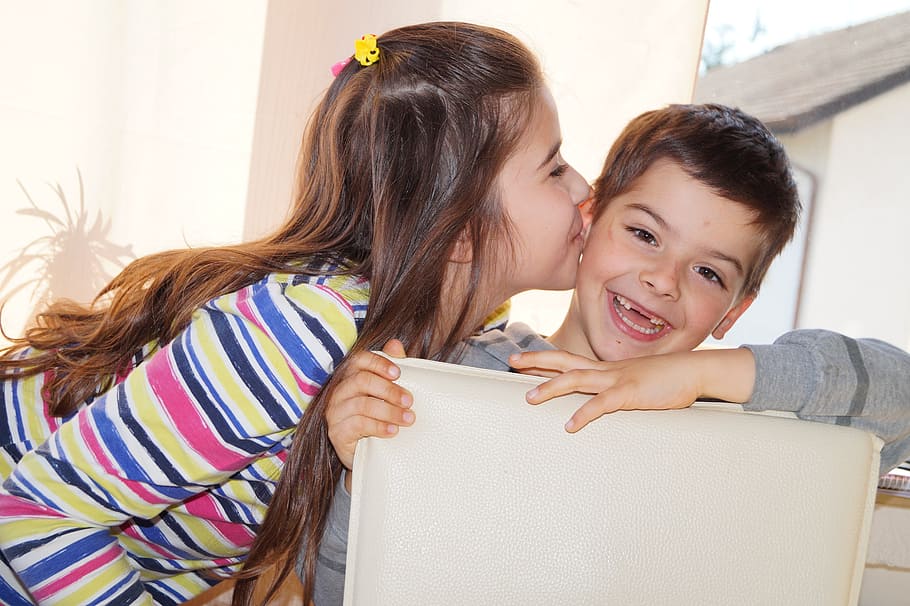 girl kisses smiling boy while sitting on gray leather dining chair during daytime, HD wallpaper