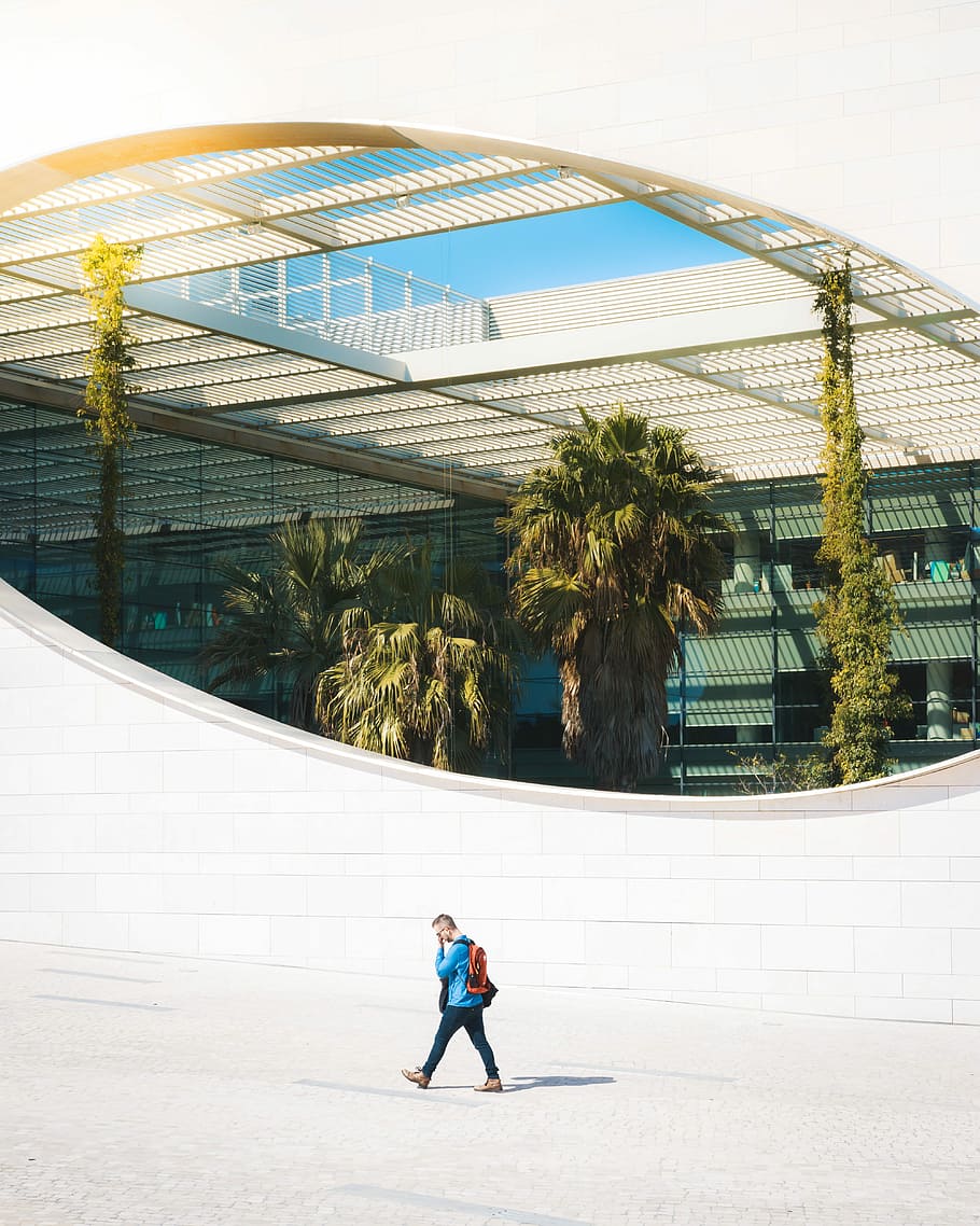 Window to the unknown, man walking beside the architectural building HD wallpaper