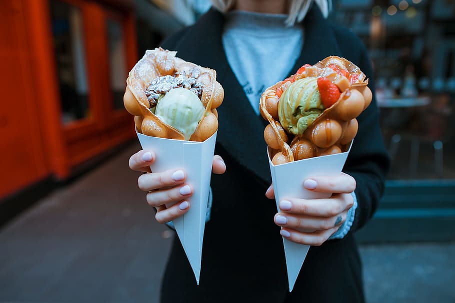 person holding two ice creams, two cone of waffle ice creams