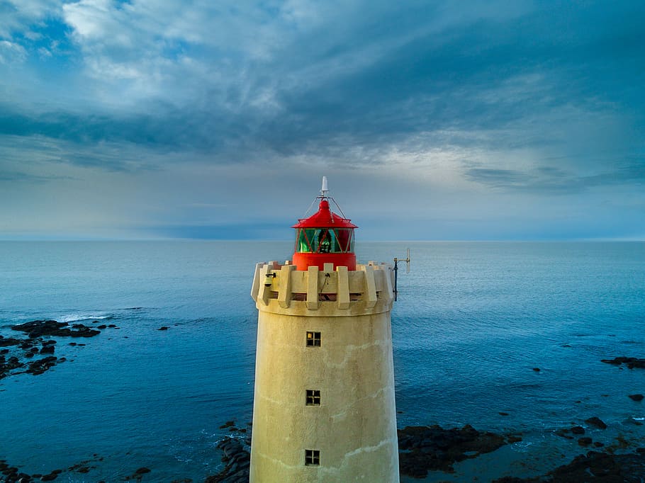 yellow and red lighthouse near body of water at daytime, photo of beige lighthouse HD wallpaper