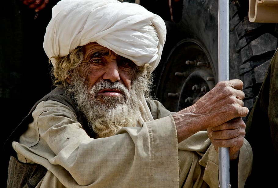 man holding grey pole, afghanistan, weathered, staring, wary