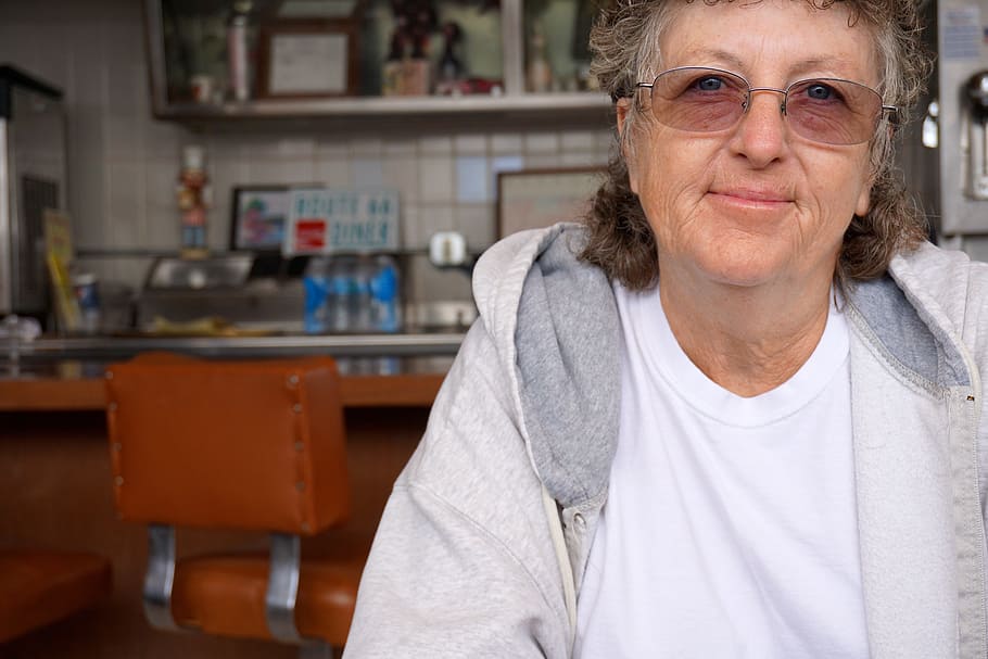 person wearing gray hoodie, senior woman, glasses, portrait, cafe