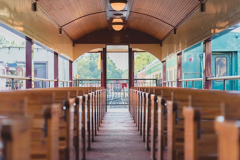 selective focus photography of building interior with brown wooden benches aligned symmetrically HD wallpaper